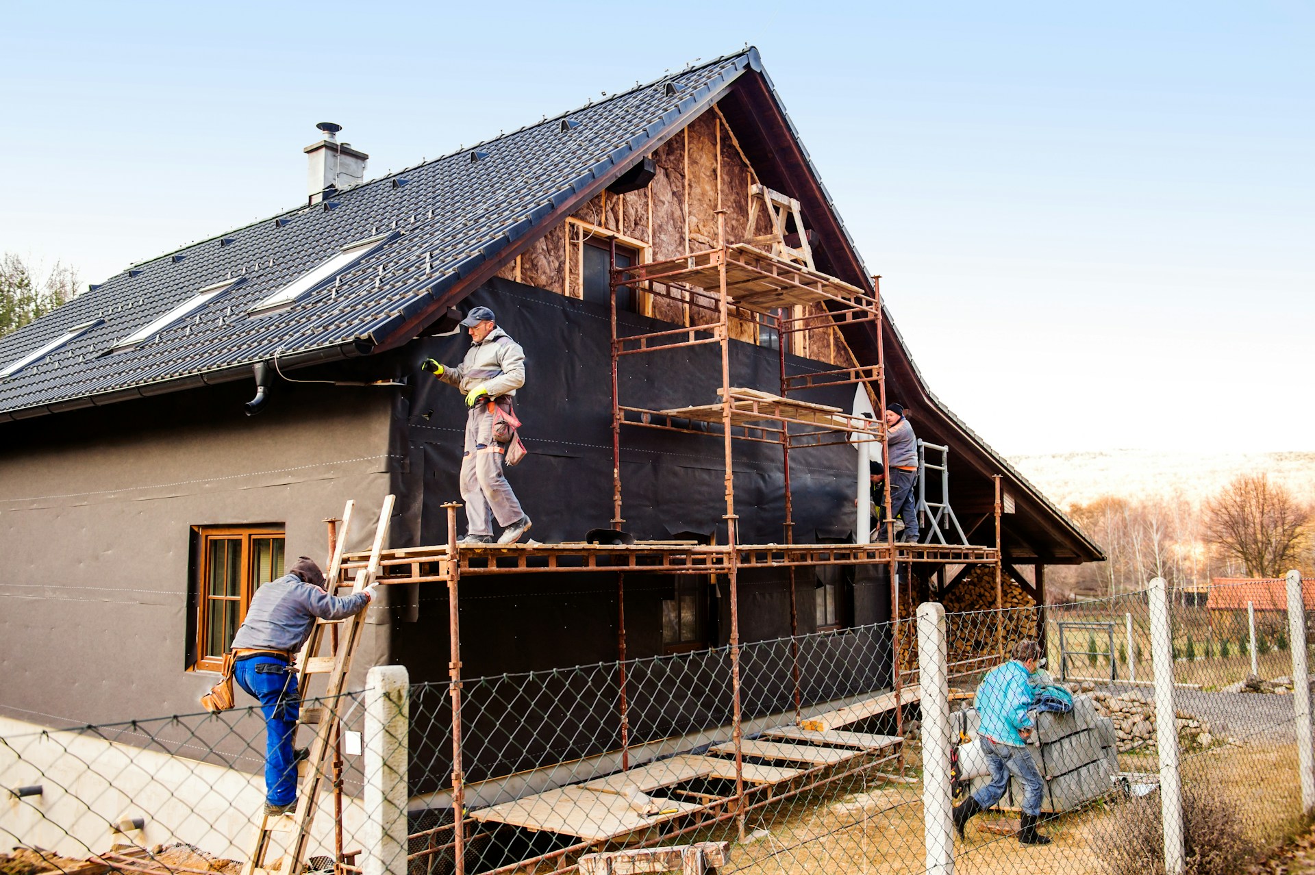 artisans en train de poser le doublage extérieur des murs d'une maison